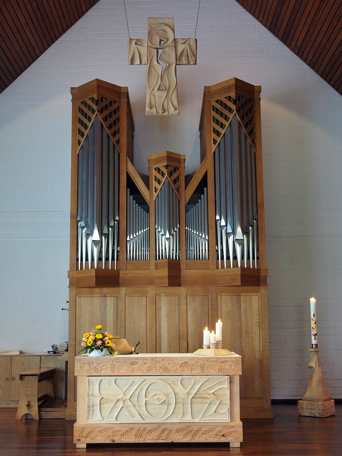 Ein Bild der Orgel der Gemeinde. Zusehen ist der Altar und das das Kreuz.